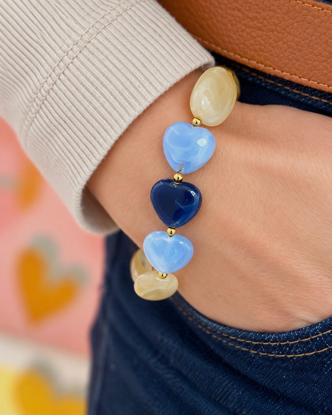 Bracelet à grosses perles ivoire marbré et trois cœurs bleus, à plat — création Lolita, Glaia Collection, Guer