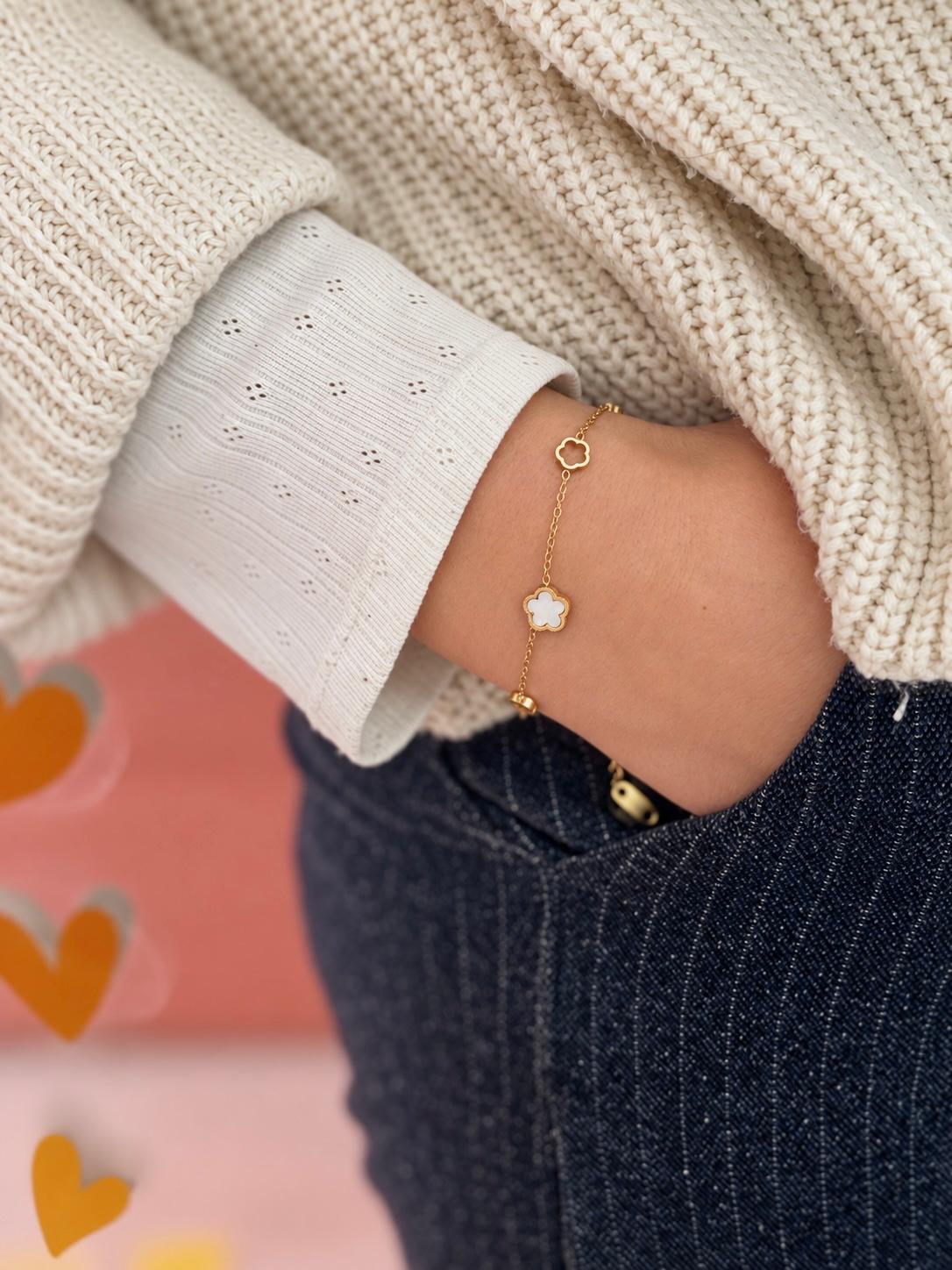 Bracelet chaîne fine dorée à fleur ajourée et fleur de nacre blanche, porté au poignet — Glaia Collection, Guer